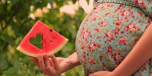 a slice of watermelon in a pregnant woman's hand
